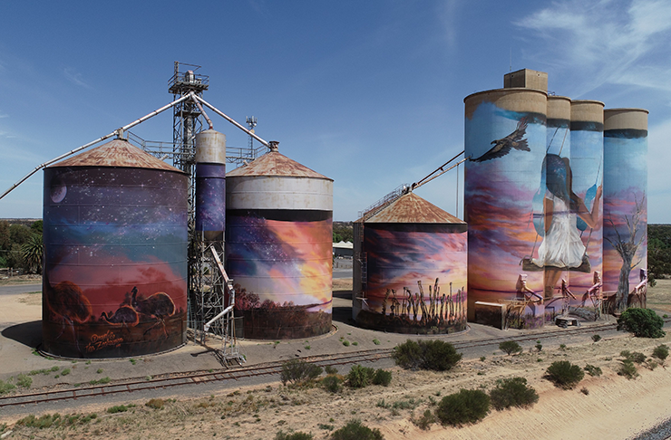 A silo with large art painted on it.