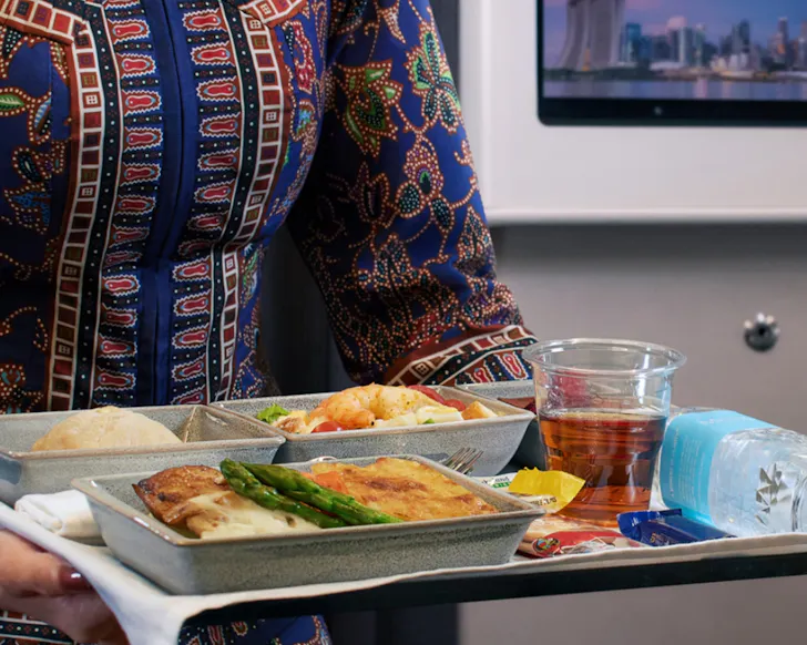 A flight attendant carrying a tray of food on Singapore Airlines