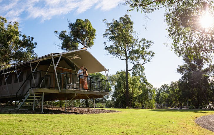a glamping tent with two people standing on the balcony