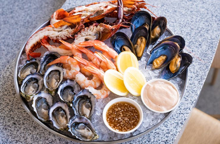 A large platter of mixed seafood on ice - prawns, mussels, oysters and bugs