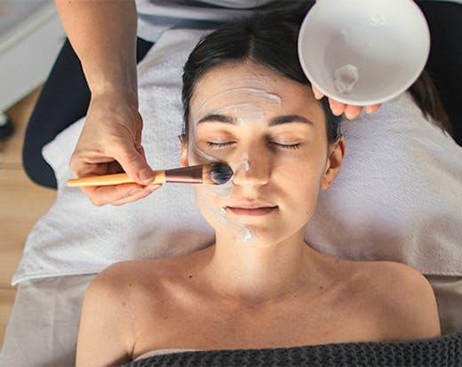 a woman getting a mask brushed on her face