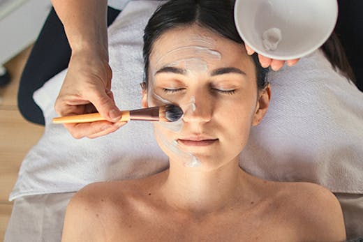 a woman getting a mask brushed on her face