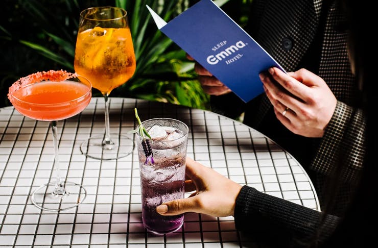 Two people dining at a white tiled table, both sipping on margaritas.