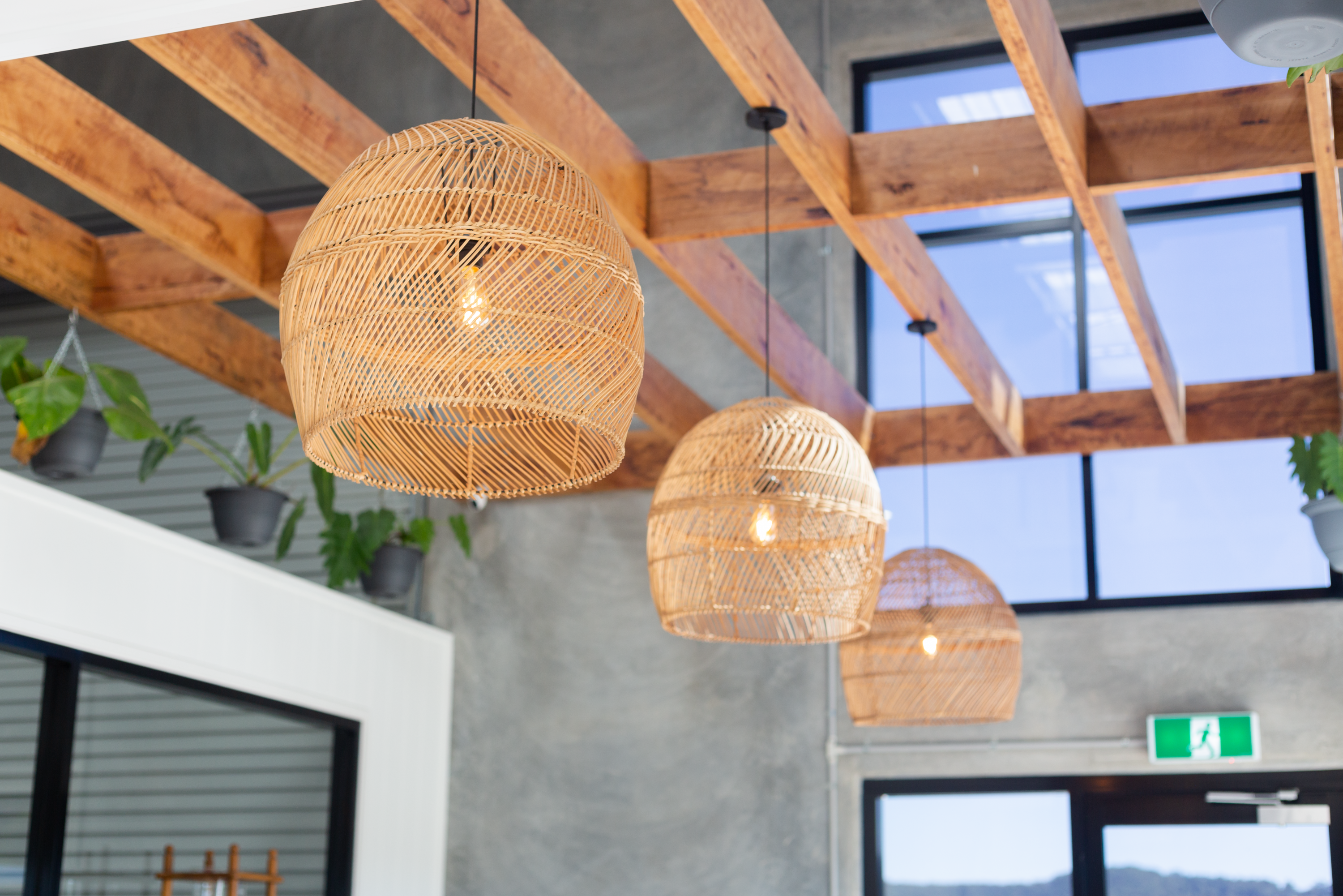 Wicker baskets around hanging bulbs against a varnished wood panelled ceiling.