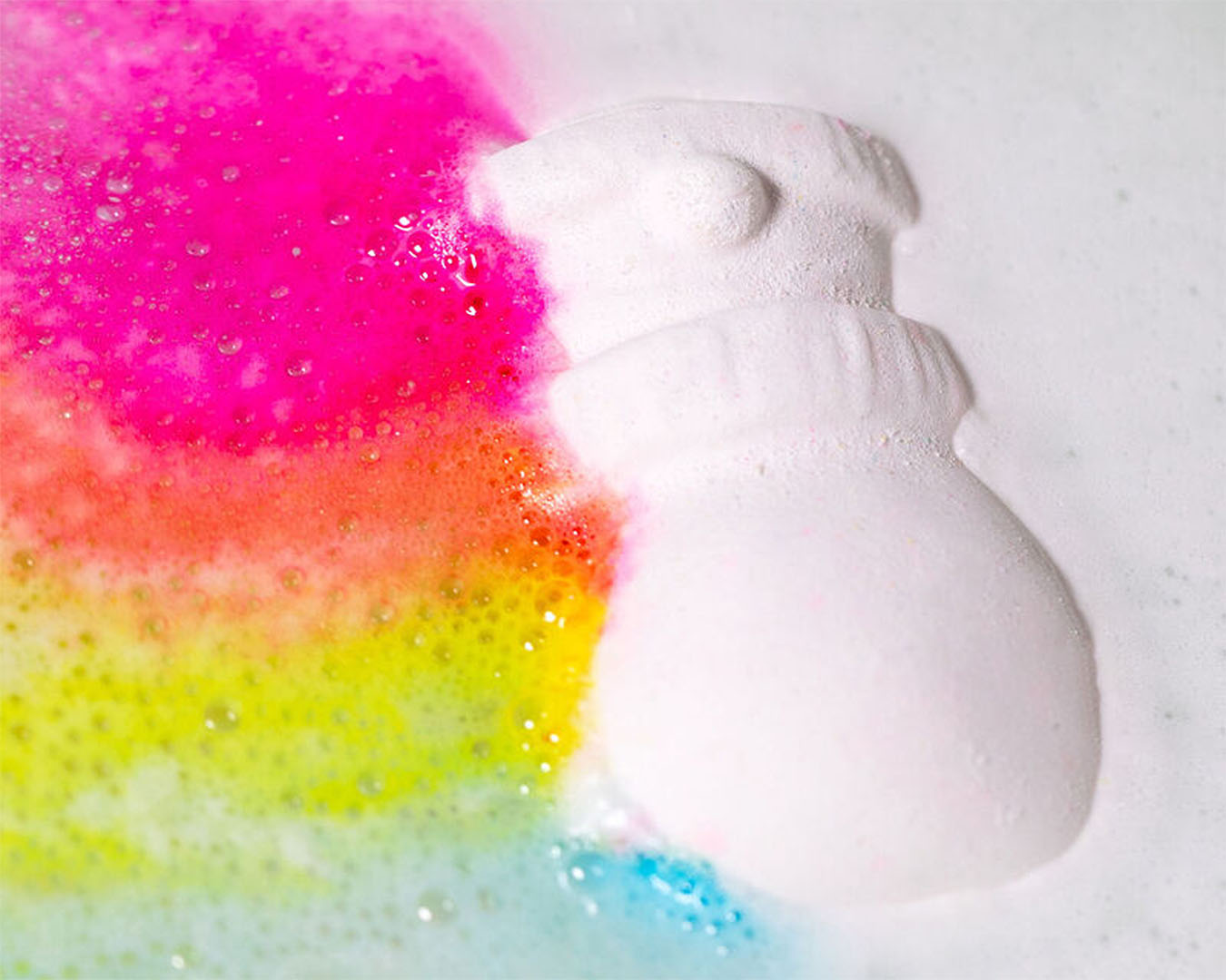 A white snowman-shaped bath bomb with a rainbow edge. 