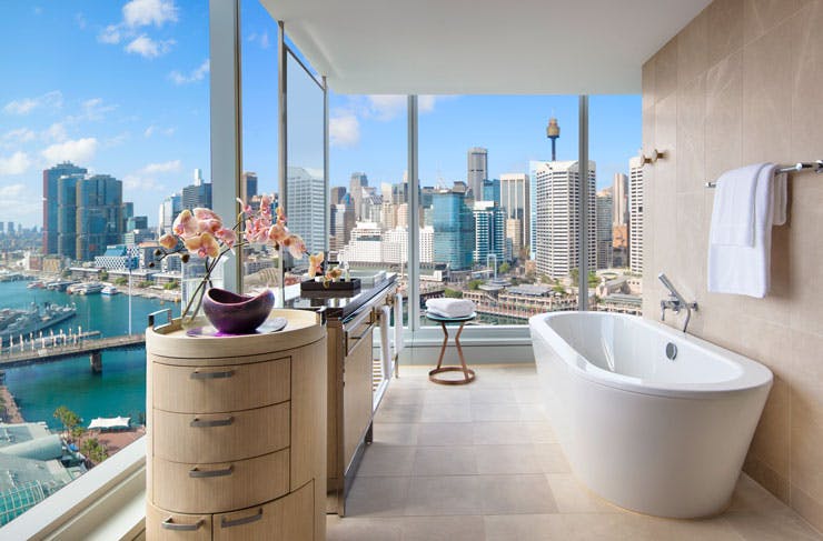 A hotel bathroom with a bathtub and views across Darling Harbour. 