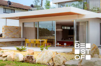 Modern beachfront home with floor-to-ceiling glass, sandstone details and an alfresco dining terrace.