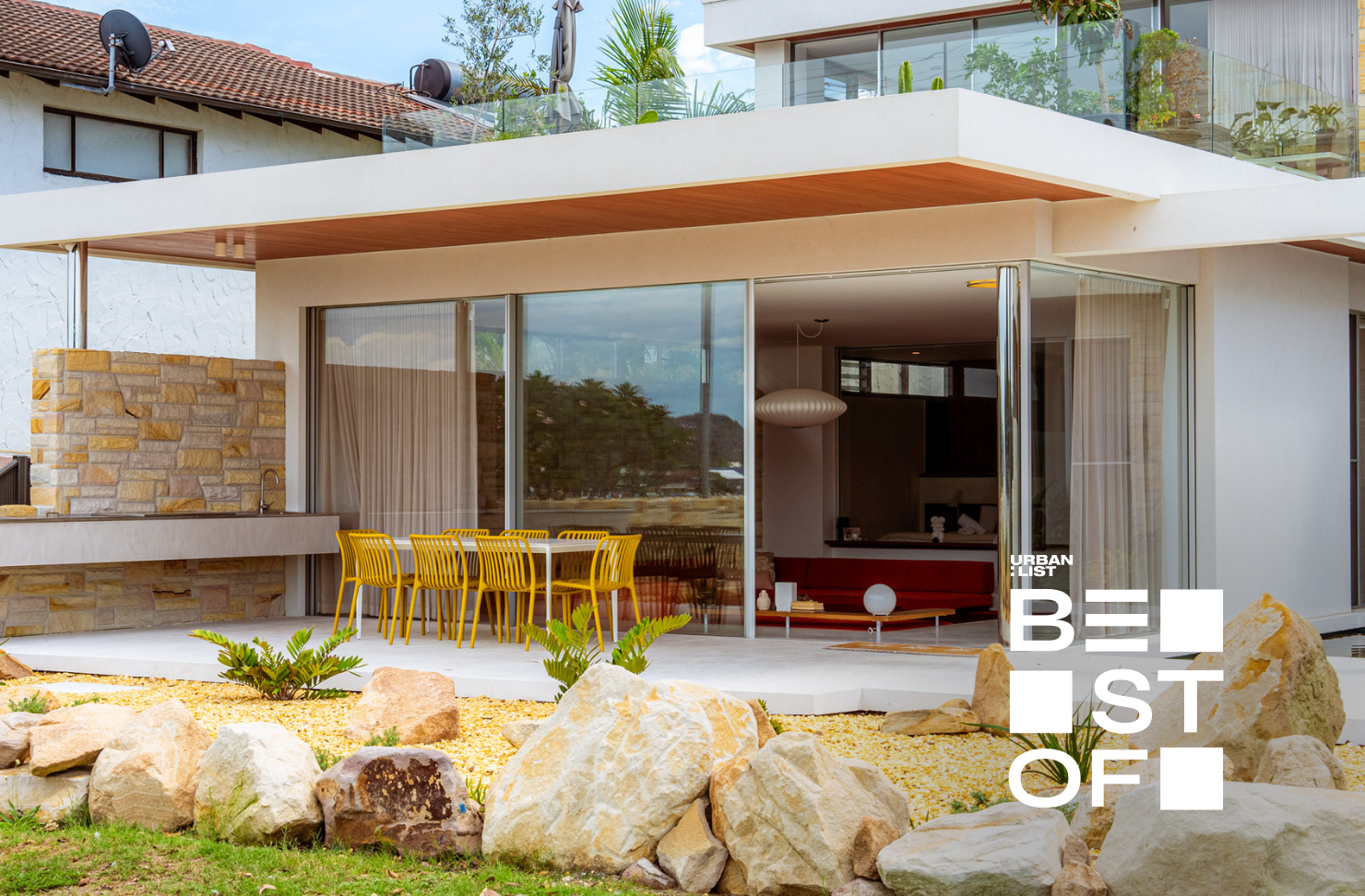 Modern beachfront home with floor-to-ceiling glass, sandstone details and an alfresco dining terrace.