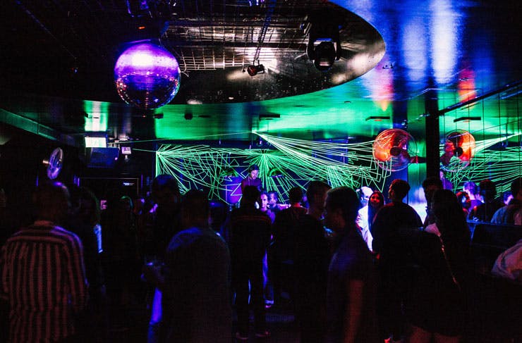 A busy dance floor with lasers and a disco ball. 