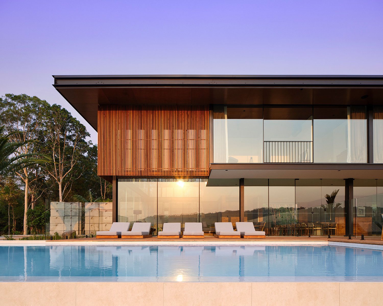 a glass-fronted house overlooking a pool'
