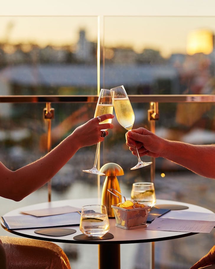 Two people drinking champagne at Songbird rooftop bar in Perth's CBD