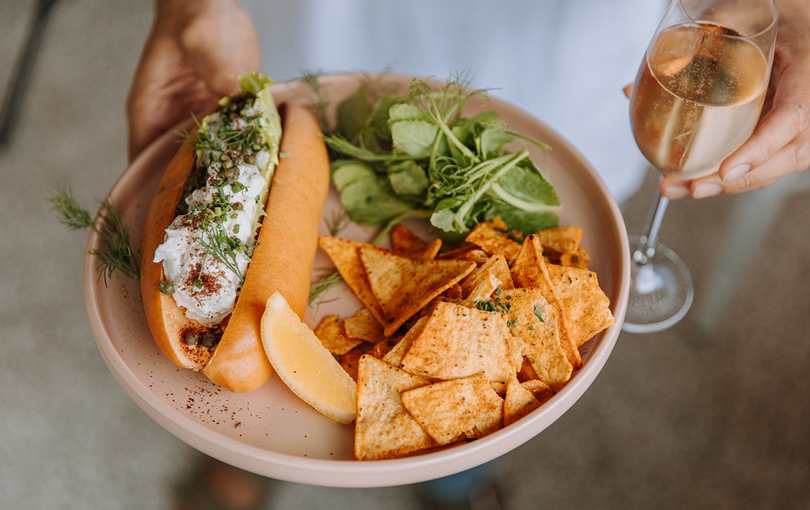 a lobster roll alongside a pile of chips