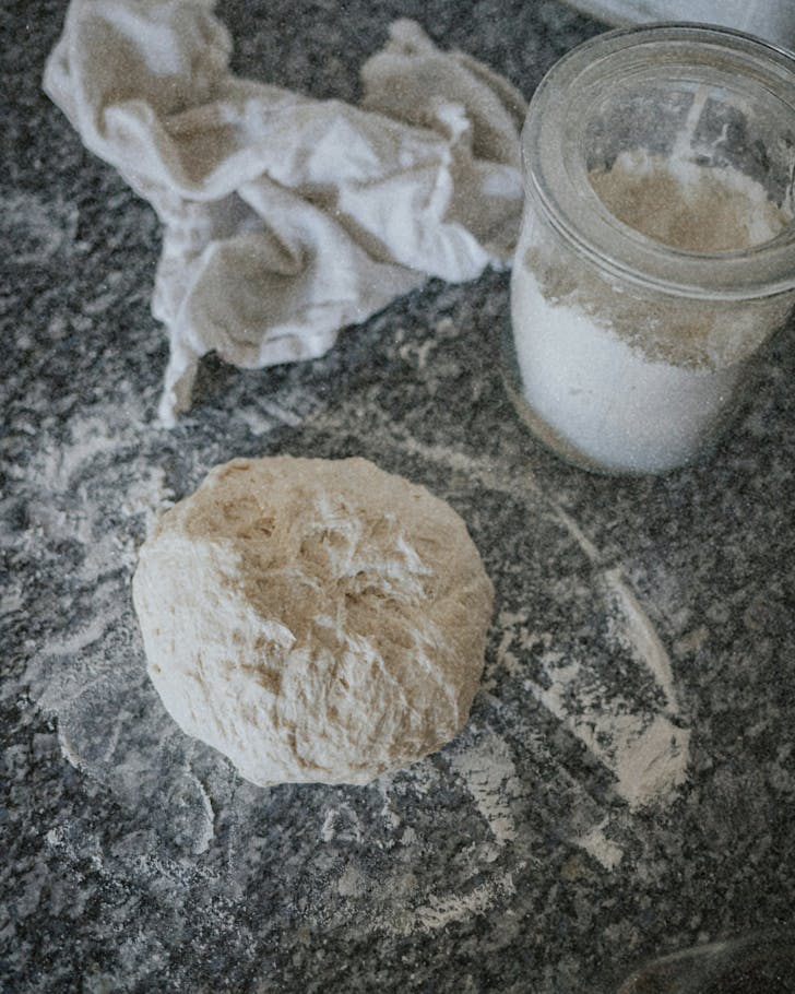 Sourdough is being rolled on a flour-sprinkled bench.