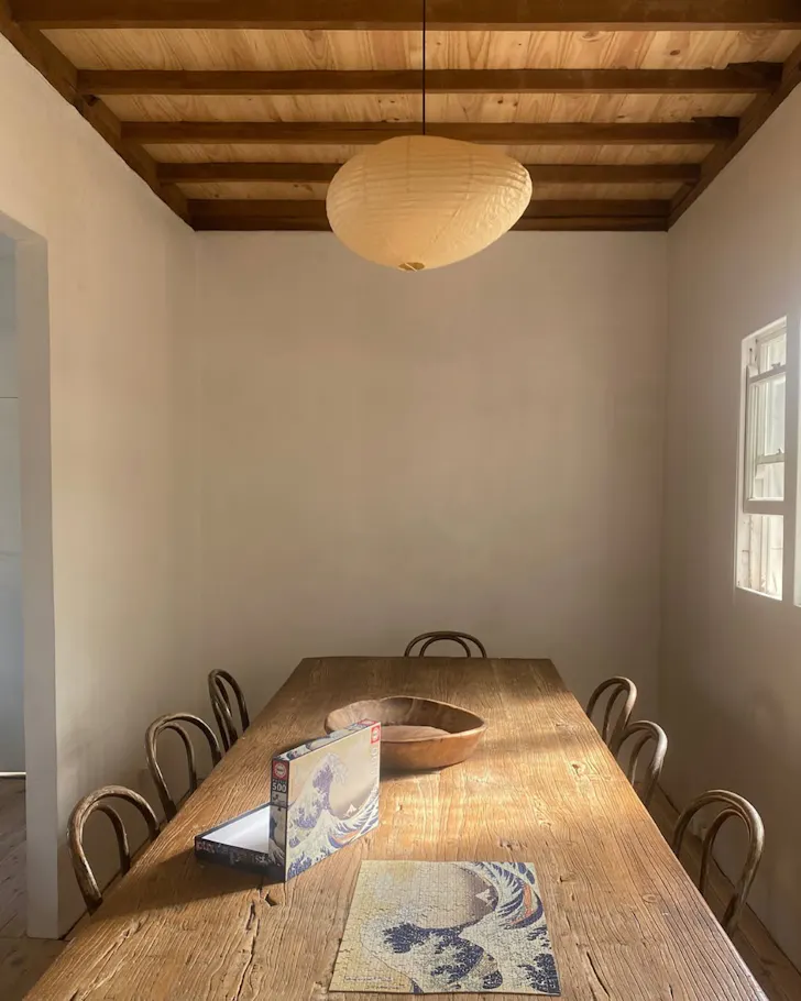 Rustic dining room with a timber table, bentwood chairs, exposed beams and soft natural light.