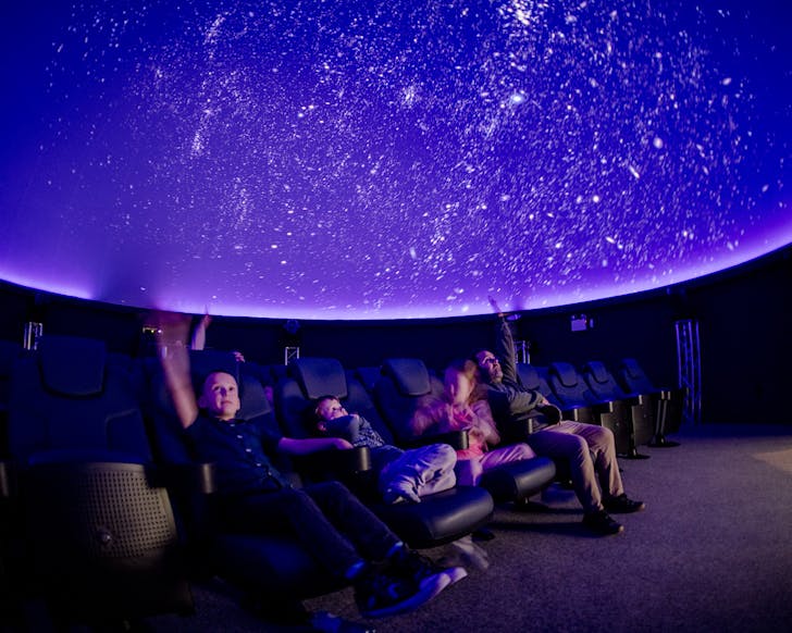 People stare up in awe at a purple Stardome starscape.