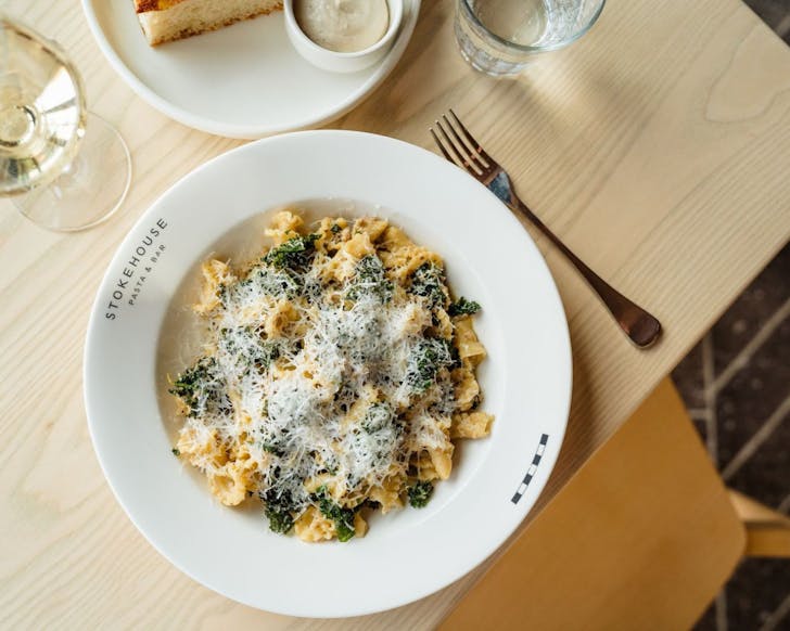 A bowl of pasta reads stokehouse on a table with other italian dishes