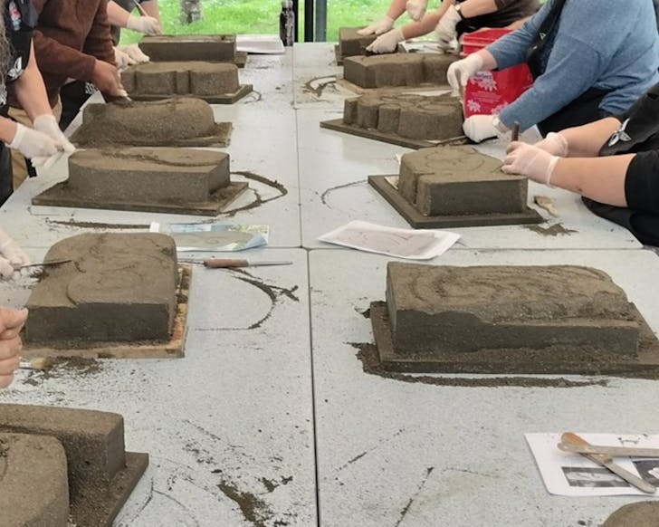 People's hands sculpting stone tablets.