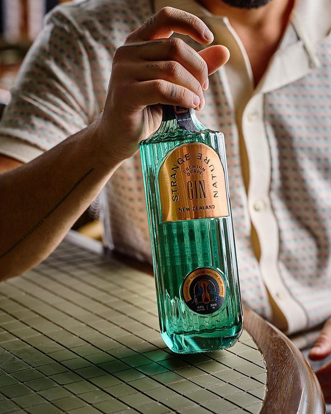 Someone holds a bottle of Strange Nature Gin, one of the best gins in NZ.