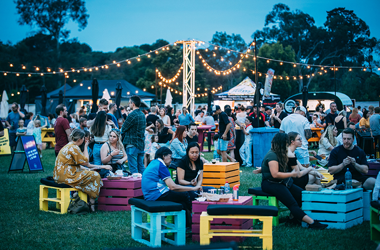 People sitting in a food truck park.