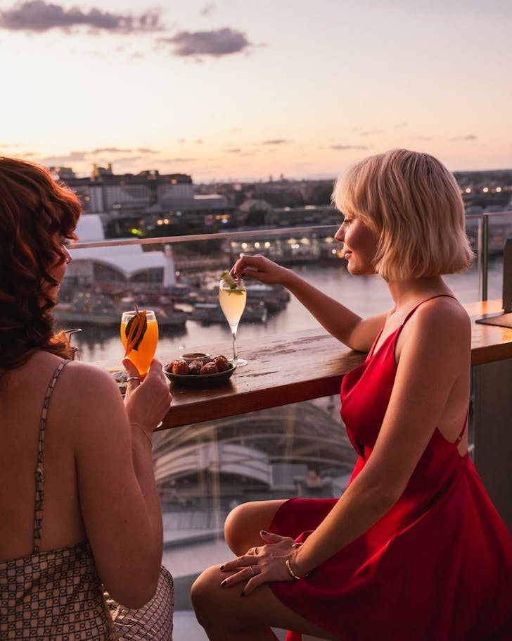 women enjoying cocktails while watching the sunset over darling harbour from zephyr bar