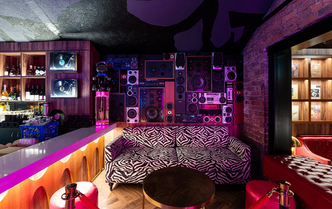 a zebra patterned couch with a wall of speakers