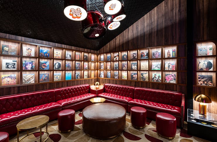 a seating area with red leather benches and record covers lining the walls