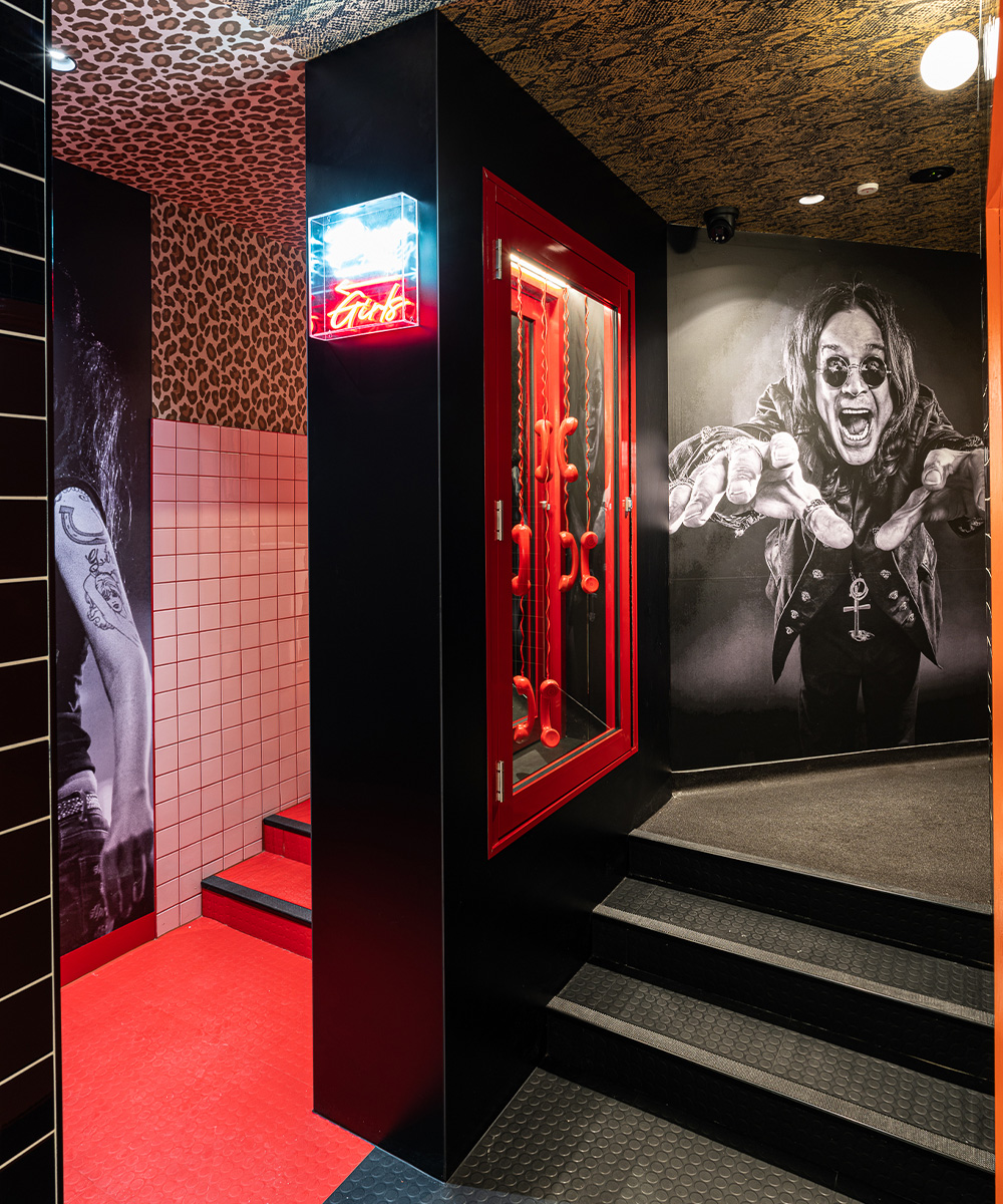 doors into bathrooms with a mural of Ozzy ozbourne and a wall of red phone handsets