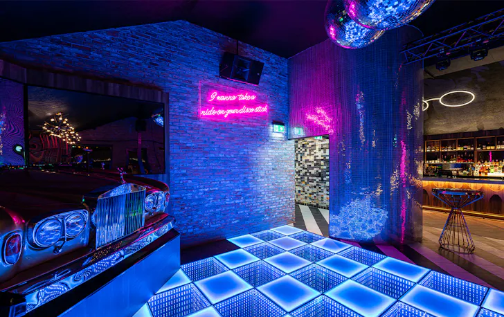 a lit up dancefloor and a dj booth in a cadilac