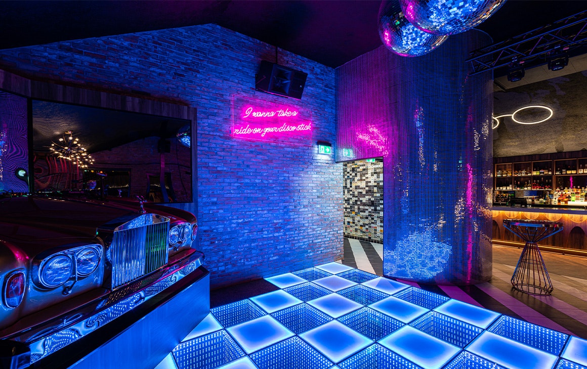 a lit up dancefloor and a dj booth in a cadilac