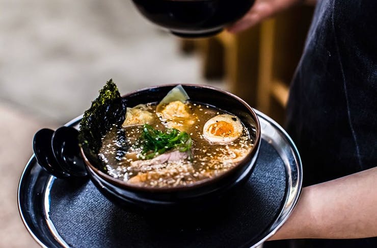 Supernormal's signature ramen being carried on a black tray.
