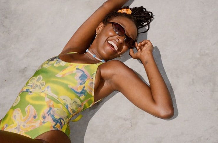 A model wearing a green and yellow patterned swimsuit