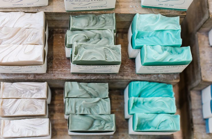 Different coloured handmade soaps on a wooden bench.