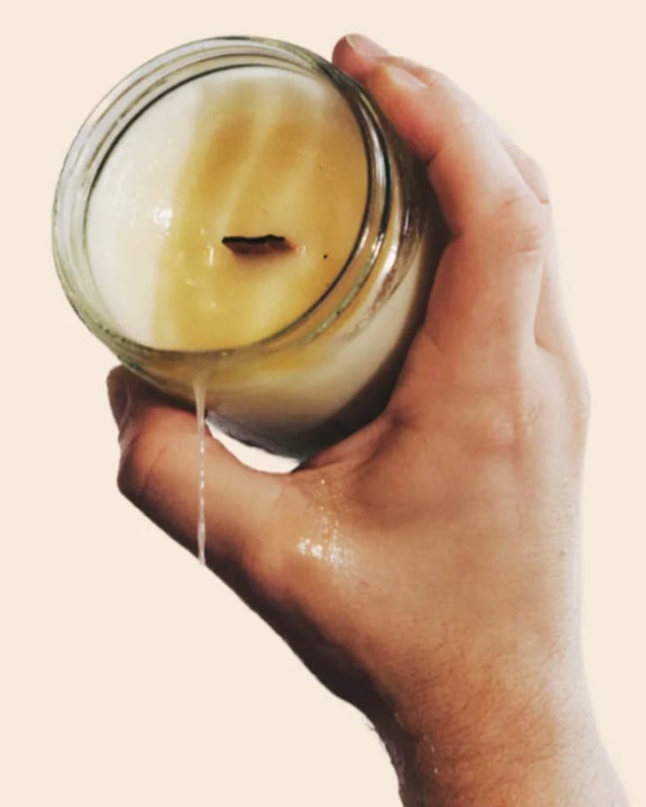 A hand holds a candle and wax drips seductively.