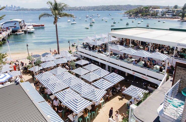 The beer garden at Watsons Bay Boutique Hotel on a sunny day, with blue and white striped umbrellas out. 