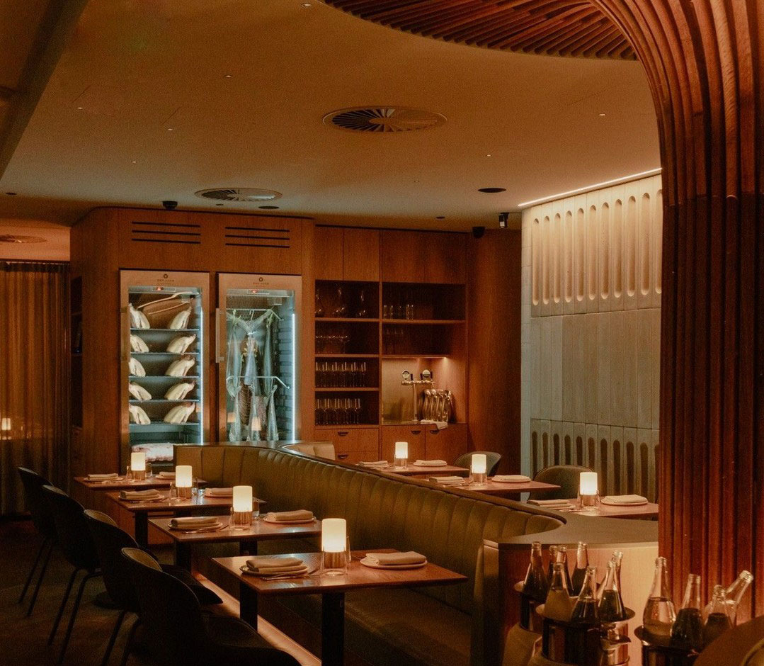 The sculptural dining room with wood accents and warmly dimmed lighting at AALIA, one of the best restaurants in Sydney