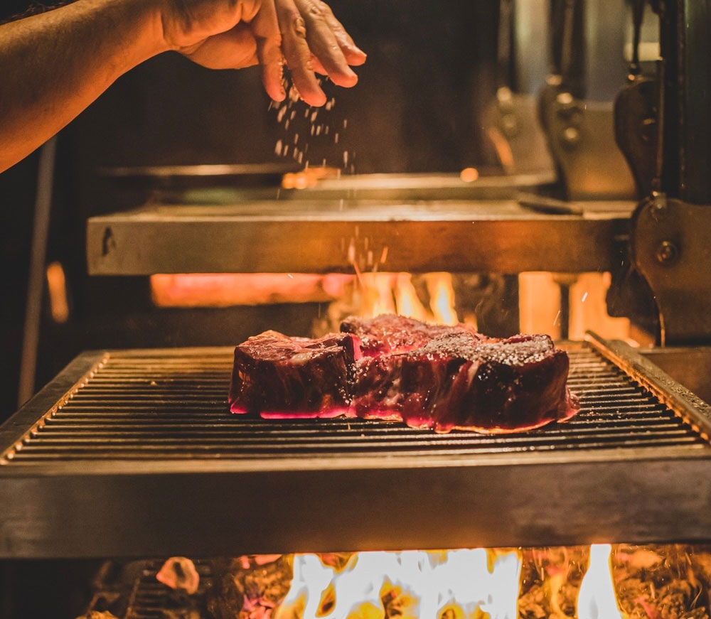 Chef Lennox Hastie seasons a steak at Firedoor, one of the best restaurants in Sydney
