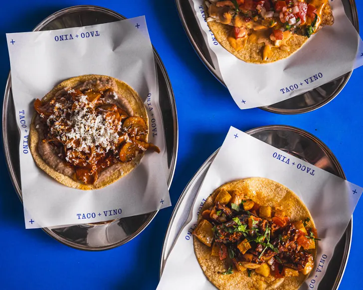 Taco + Vino Gaonera tacos on a royal blue table.