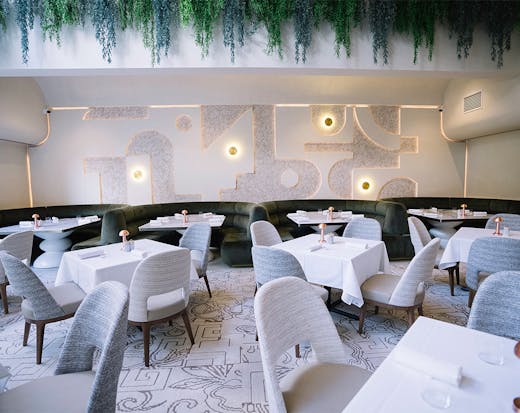 a dining area at tama brisbane, with tables in front of round, green booths