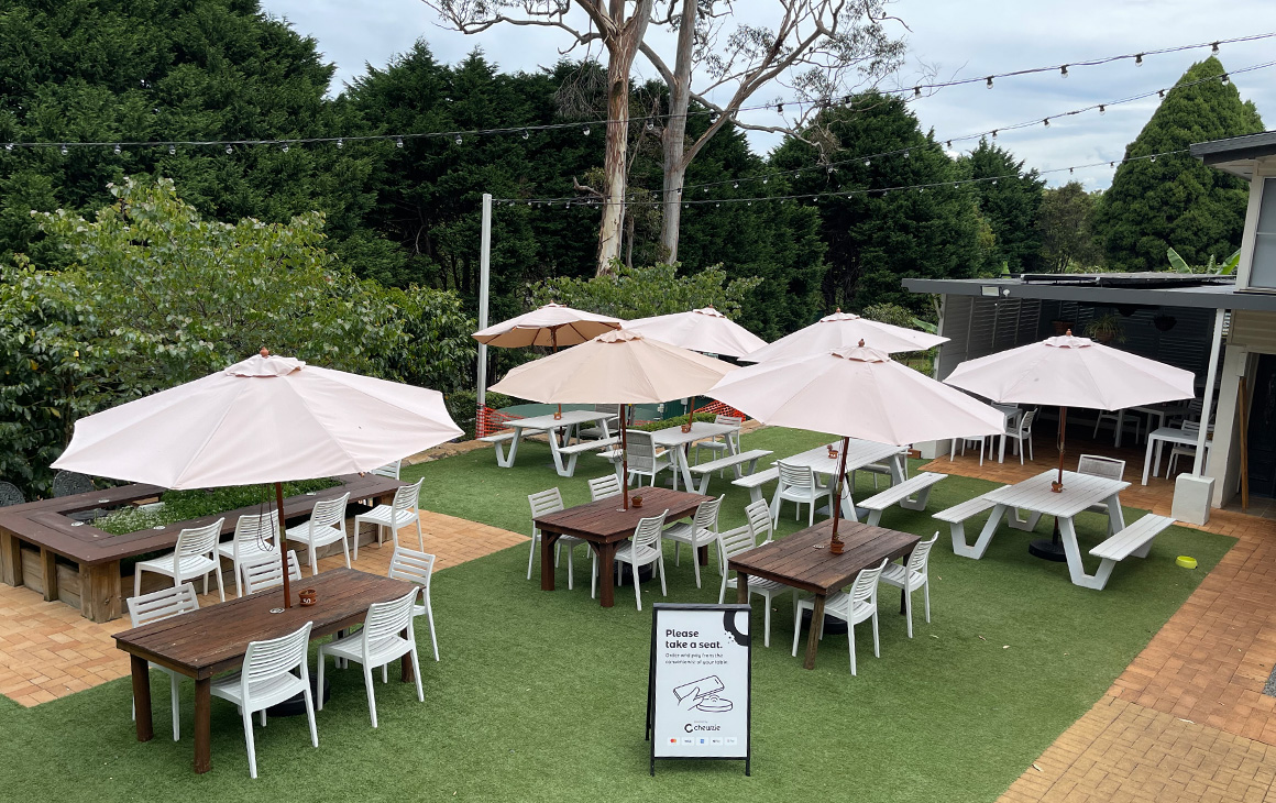 an outdoor dining area with umbrellas and festoon lighting