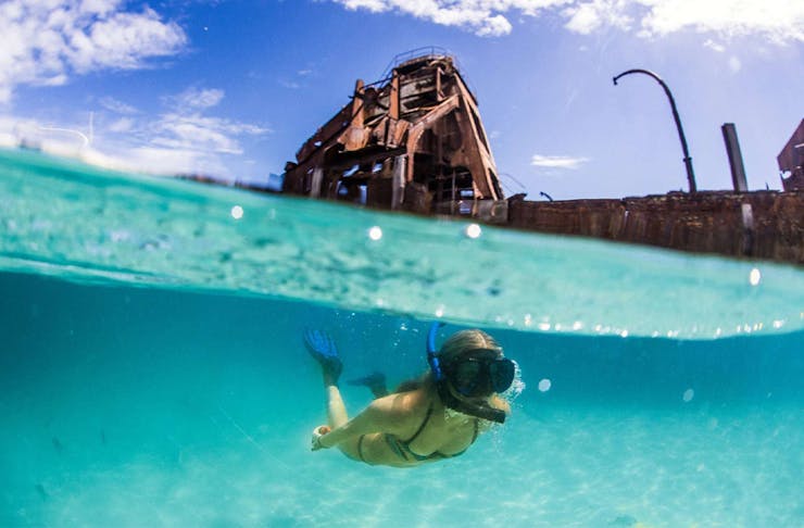a woman snorkelling under shipwrecks