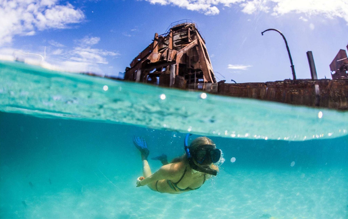 a woman snorkelling under shipwrecks