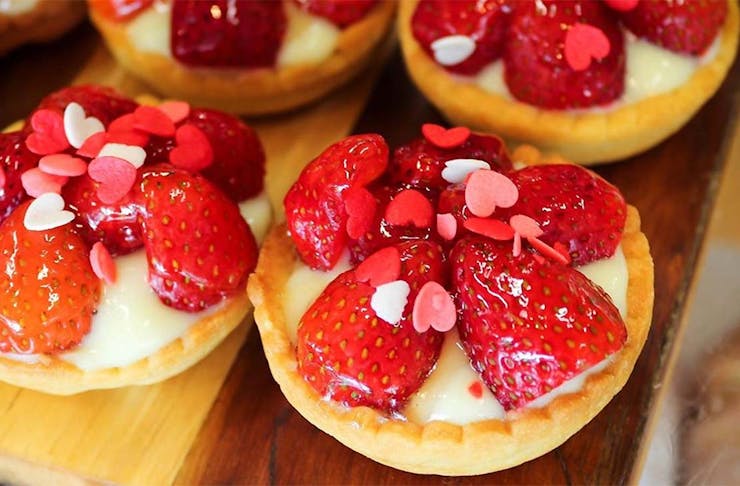 Vegan glazed strawberry tarts with little red hearts on top by Tart Bakery