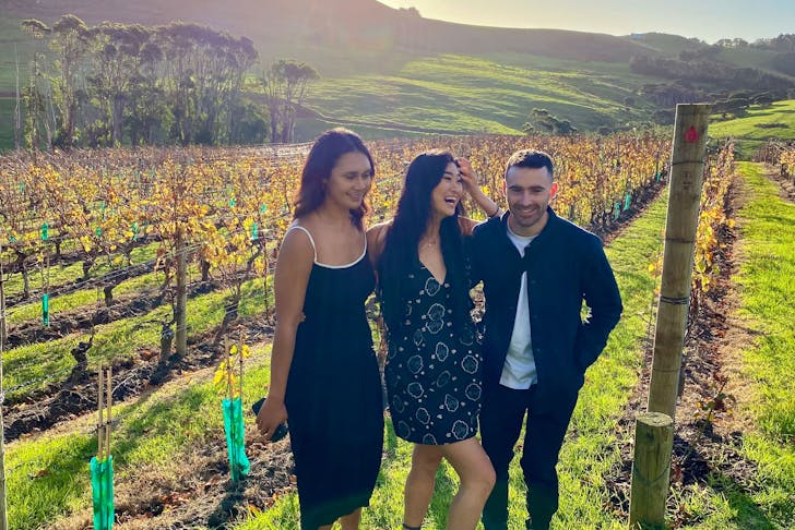 Three friends smiling in a vineyard on Waiheke Island in Auckland