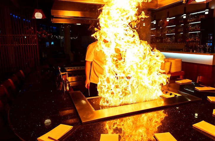 a man behind a tower of flames on a brisbane teppanyaki grill