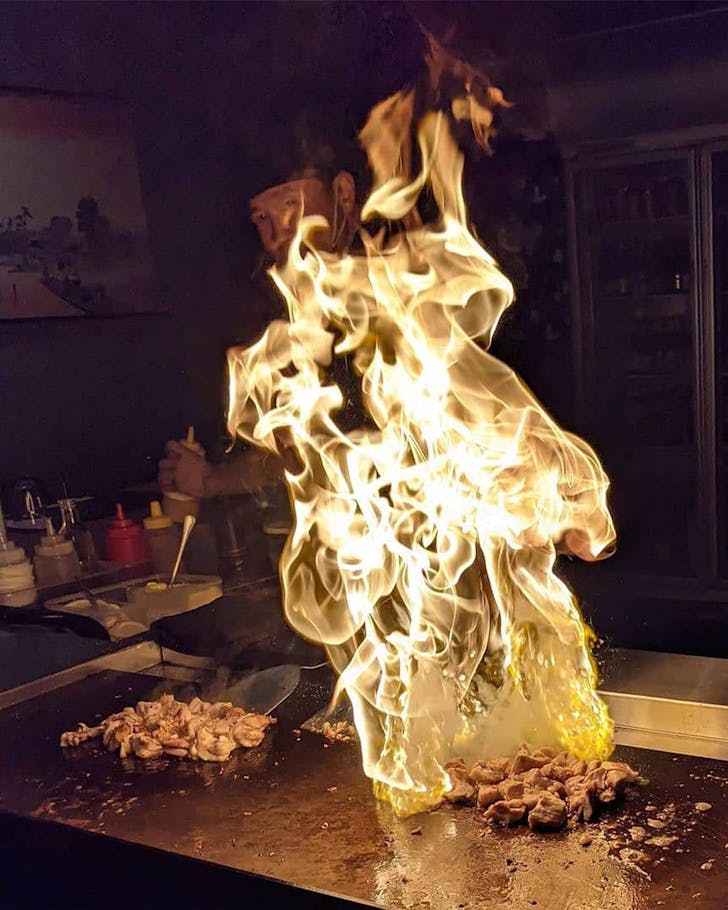 a chef cooking meat on a fiery grill at koya teppanyaki restaurant in brisbane