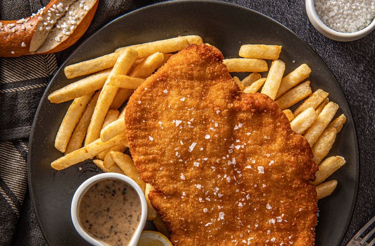A plate of schnitzel with hot chips. 