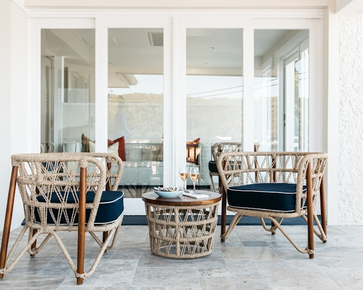 Two chairs and a table on a balcony at The Boat House Patonga some of the best Central Coast accommodation