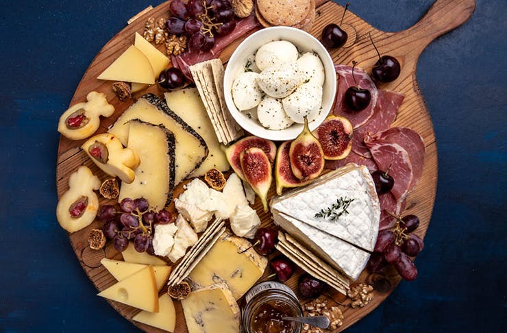 A cheese platter stacked with various cheeses.