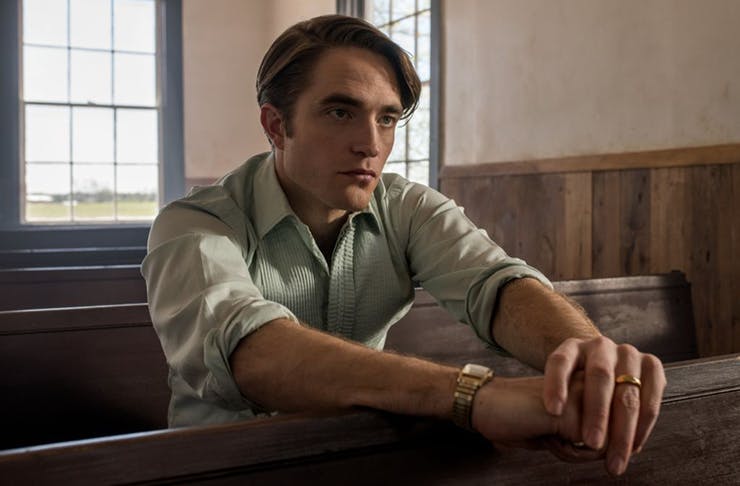 Robert Pattinson sitting in a church on the set of The Devil All The Time.