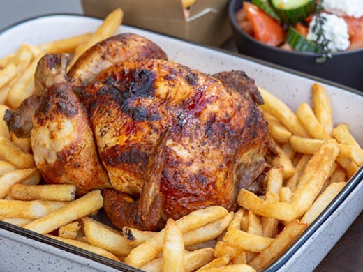 A rotisserie roasted chicken on a bed of chips from The Hot Bird in Cheltenham.